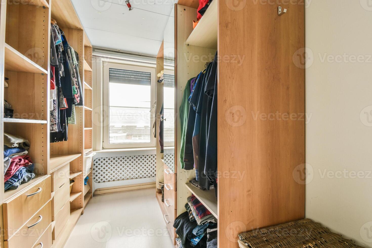 A walk in closet with clothes and a basket photo