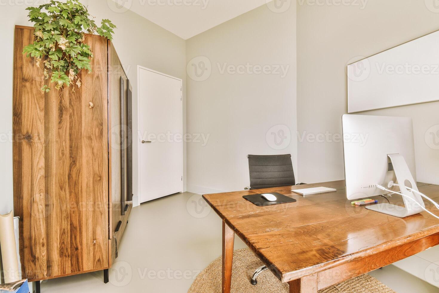 A wooden desk with a computer and a plant photo