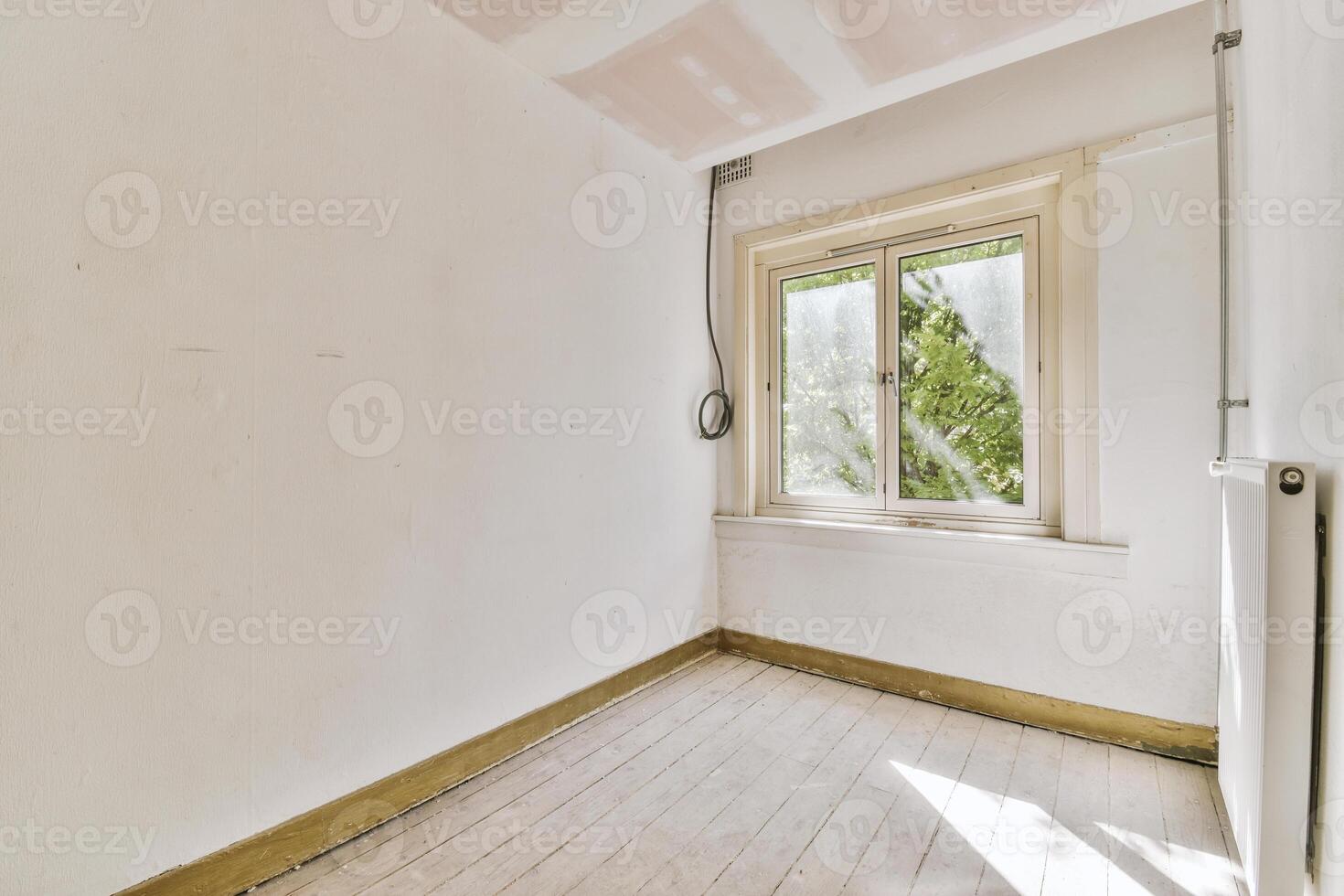 An empty room with a window and a radiator photo