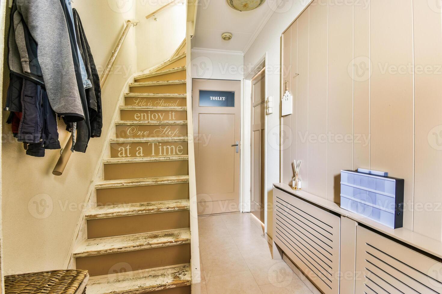 A hallway with a wooden staircase and a coat rack photo