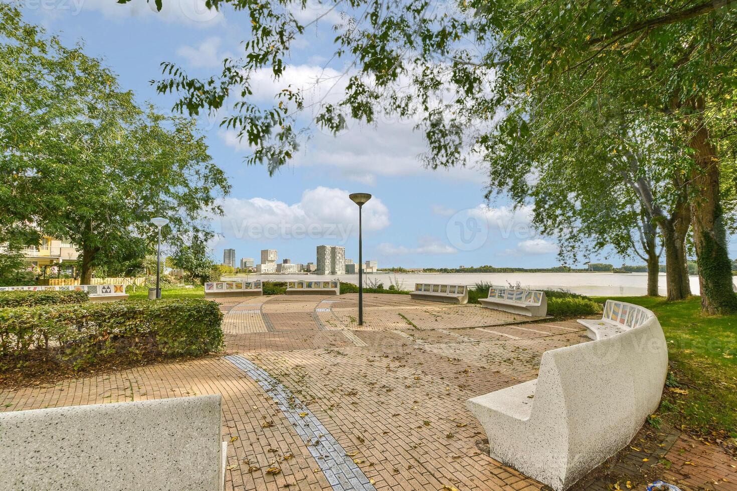 A park with benches and trees in front of a building photo