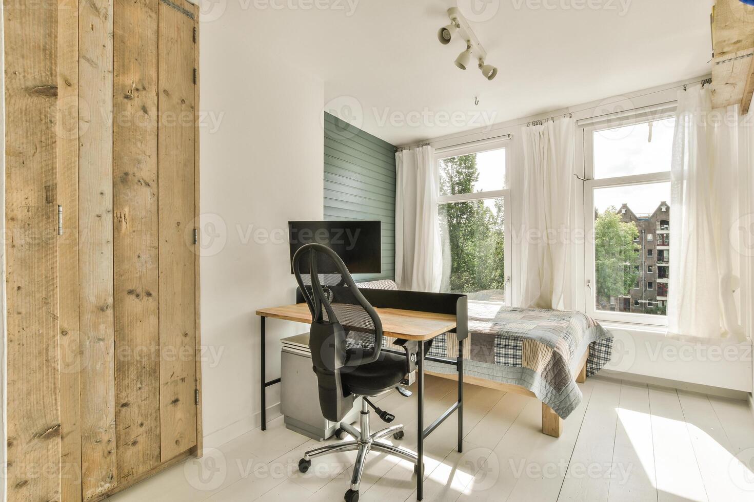 A bedroom with a desk and chair in front of a window photo