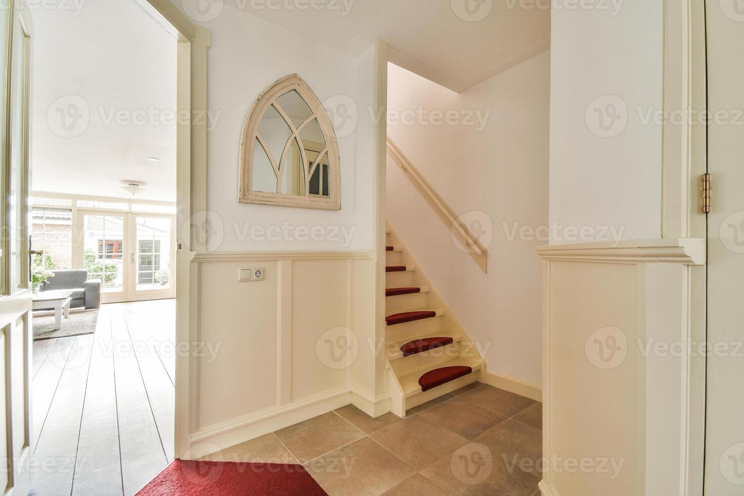 A hallway with a red carpet and white walls photo