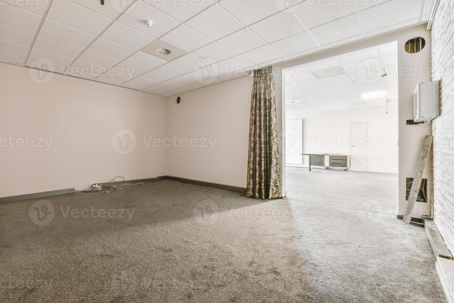 An empty room with a white wall and carpet photo