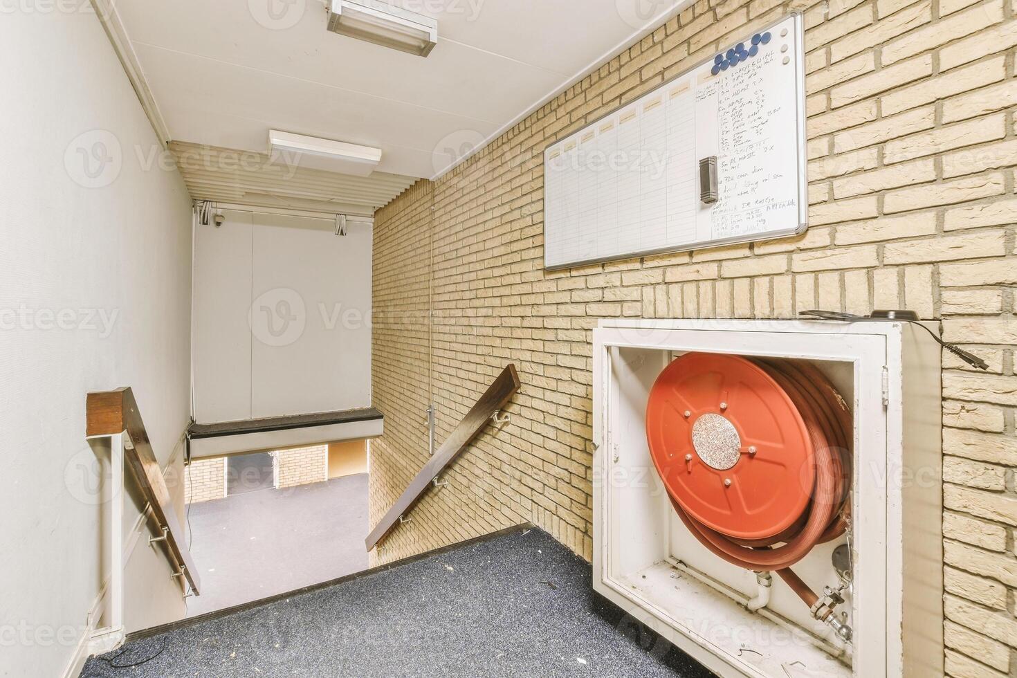 A hallway with a red fire hose and a wall photo
