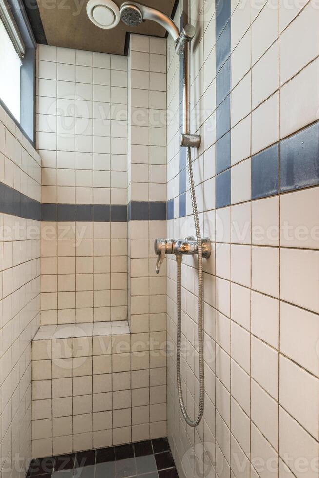 A shower with a shower head and a bench photo