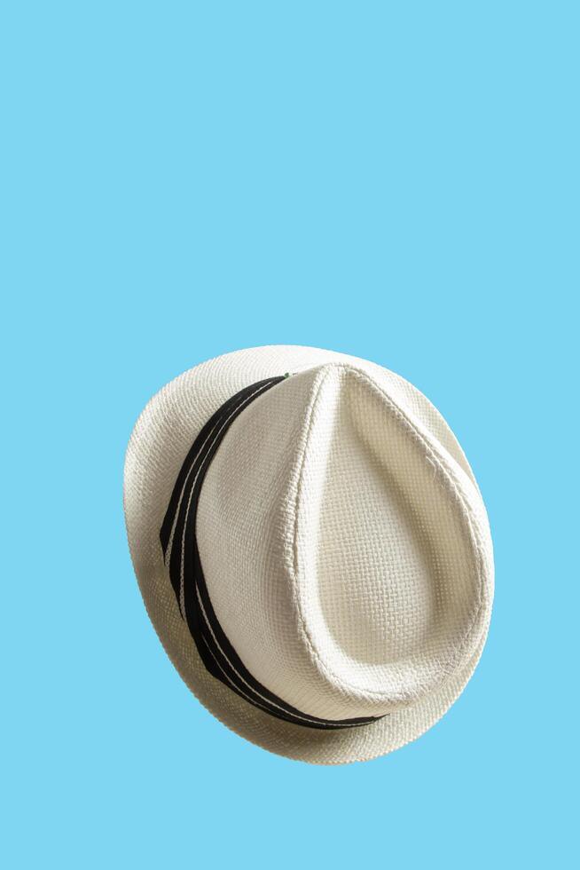portrait of flying straw hat with black ribbon strap, vintage clipart photo of the use of ivory white straw isolated on blue