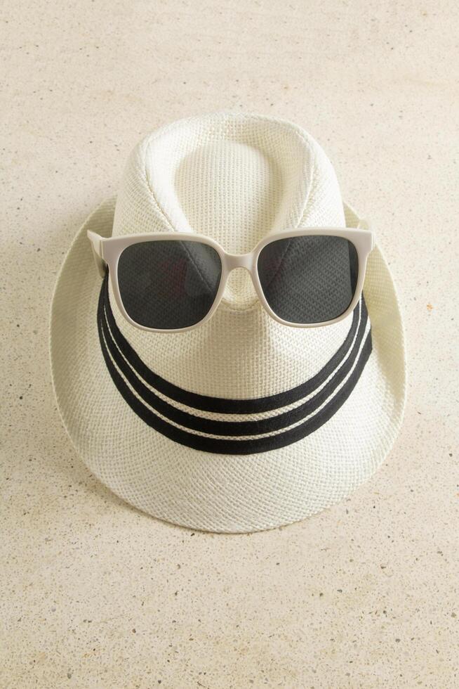 portrait from above of casual vintage hat black ribbon stripe with black and white sunglasses on textured table photo