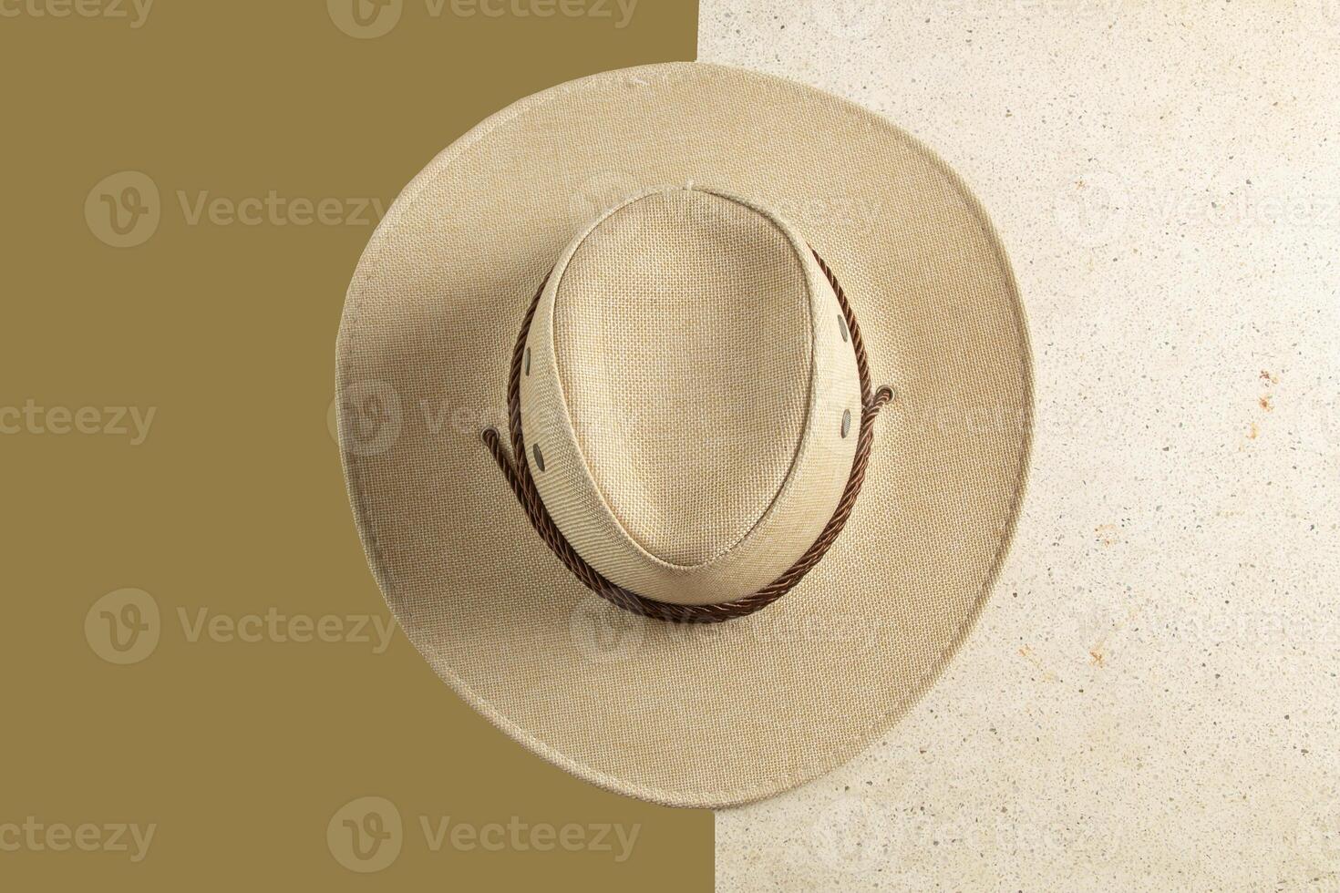 Close-up photo of a man's cowboy hat facing upwards, his hat is on a marble textured table and moss green background, clipping path
