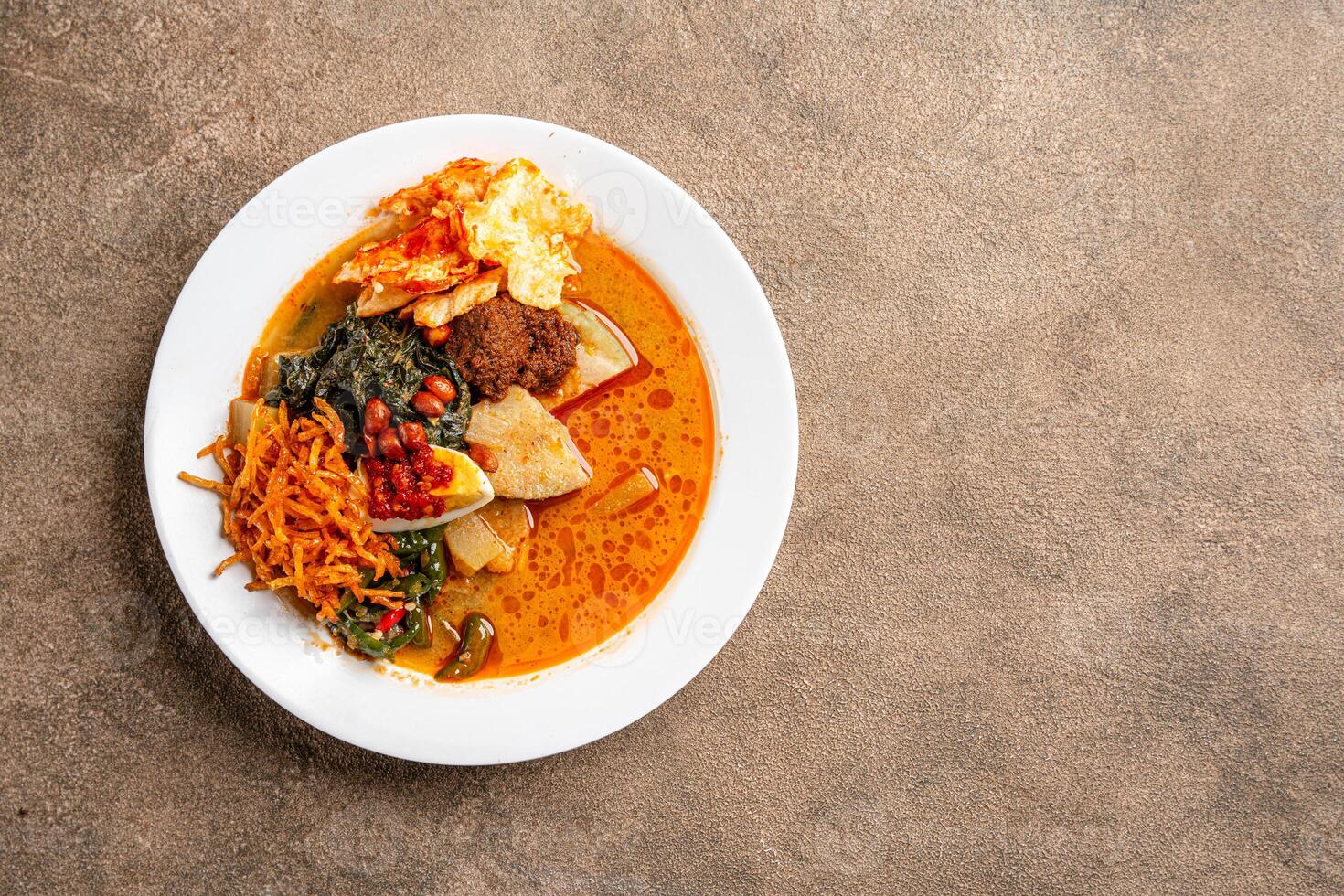 Lontong sayur or vegetable rice cake is an Indonesian traditional rice dish made of pieces of lontong served in coconut milk soup with shredded chayote, tempeh, tofu, hard-boiled egg, sambal, rendang photo