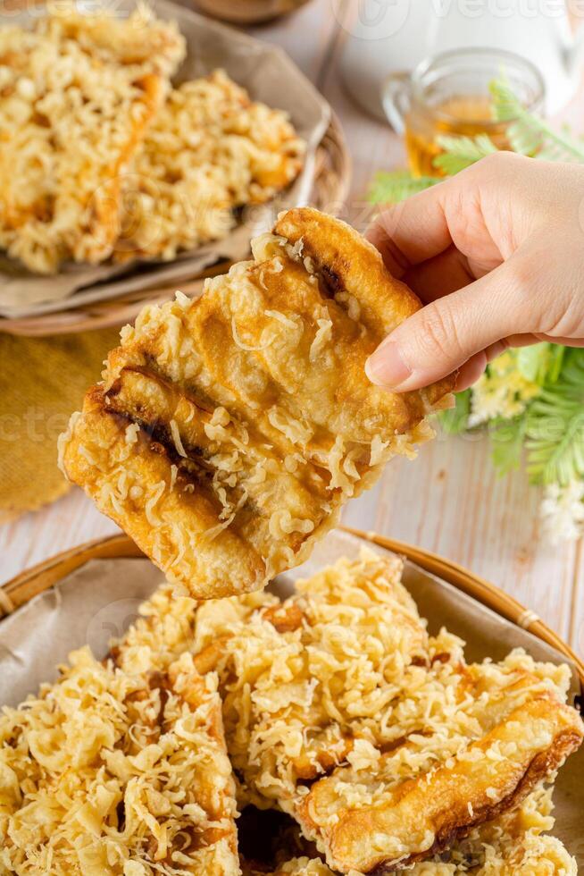 Pisang goreng Coklat Keju is a fritter made by deep frying battered plantain in hot oil. The batter most commonly uses a combination of flour, either wheat, rice flour, tapioca or bread crumb. photo