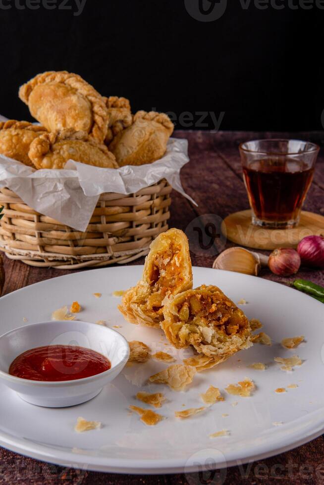 Curry puff or Pastel goreng. it is a small pie consisting of curry with chicken and potatoes in a deep fried or baked pastry shell photo