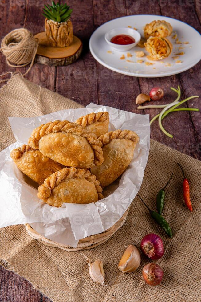 Curry puff or Pastel goreng. it is a small pie consisting of curry with chicken and potatoes in a deep fried or baked pastry shell photo