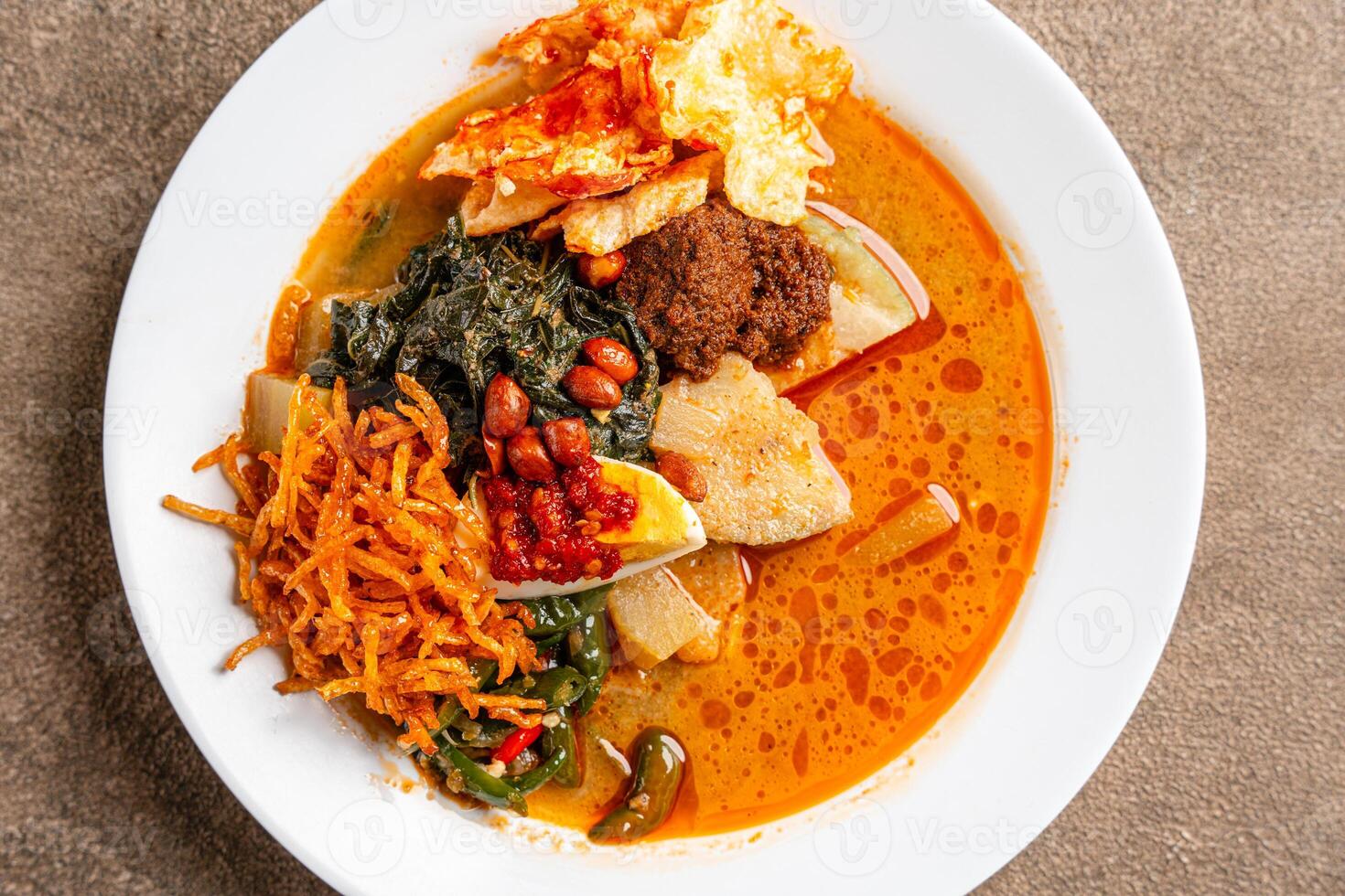 Lontong sayur or vegetable rice cake is an Indonesian traditional rice dish made of pieces of lontong served in coconut milk soup with shredded chayote, tempeh, tofu, hard-boiled egg, sambal, rendang photo