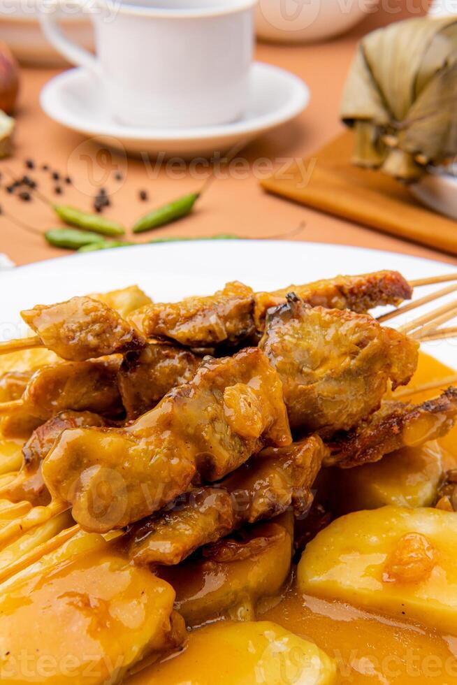Pork Satay served with a spicy Padang sauce and slices of lontong or rice cakes garnished with a sprinkle of crisp fried shallot photo
