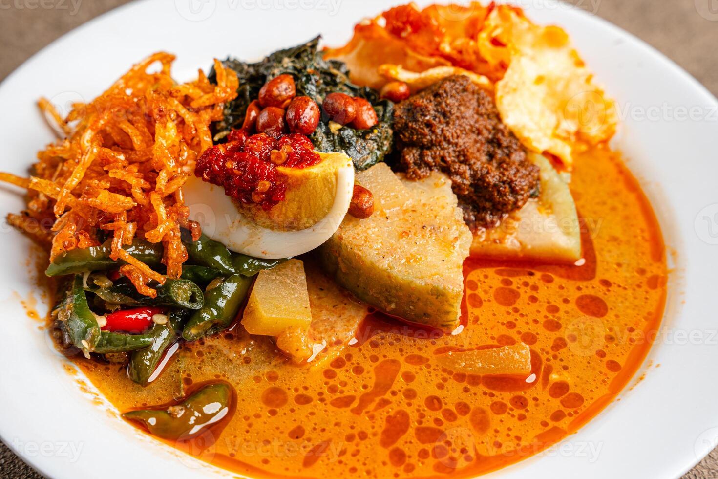 Lontong sayur or vegetable rice cake is an Indonesian traditional rice dish made of pieces of lontong served in coconut milk soup with shredded chayote, tempeh, tofu, hard-boiled egg, sambal, rendang photo