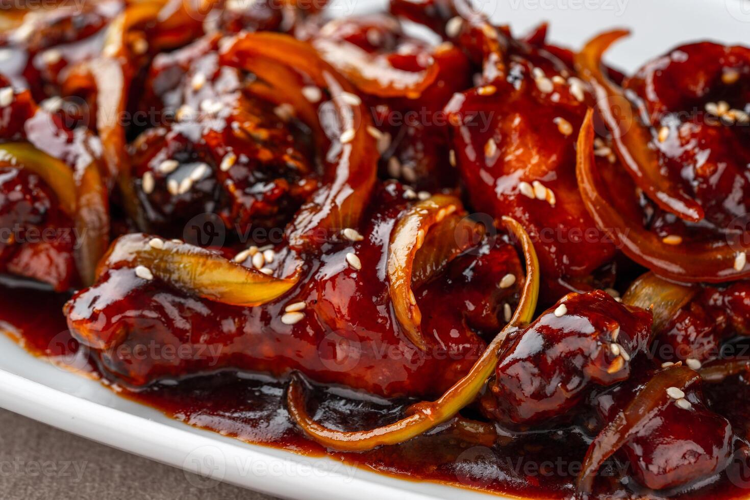 ayam goreng mentega or fried chicken with soy sauce, butter and onion served on white plate. photo