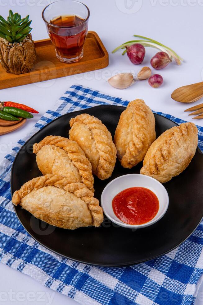 Curry puff or Pastel goreng. it is a small pie consisting of curry with chicken and potatoes in a deep fried or baked pastry shell photo