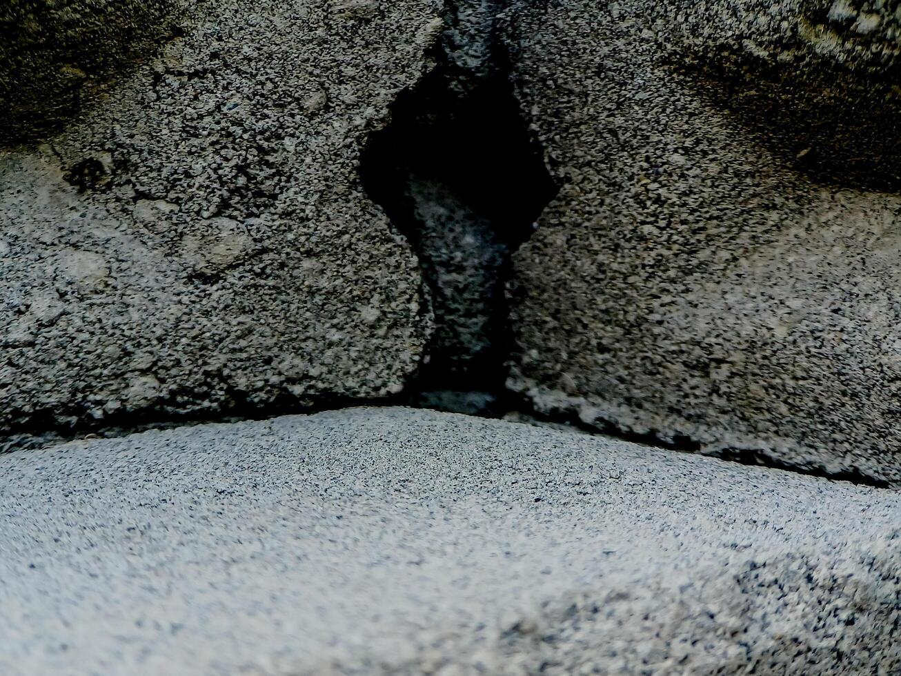 weathered concrete surface, showcasing the rough texture, cracks, and shadows created by its uneven surface. photo