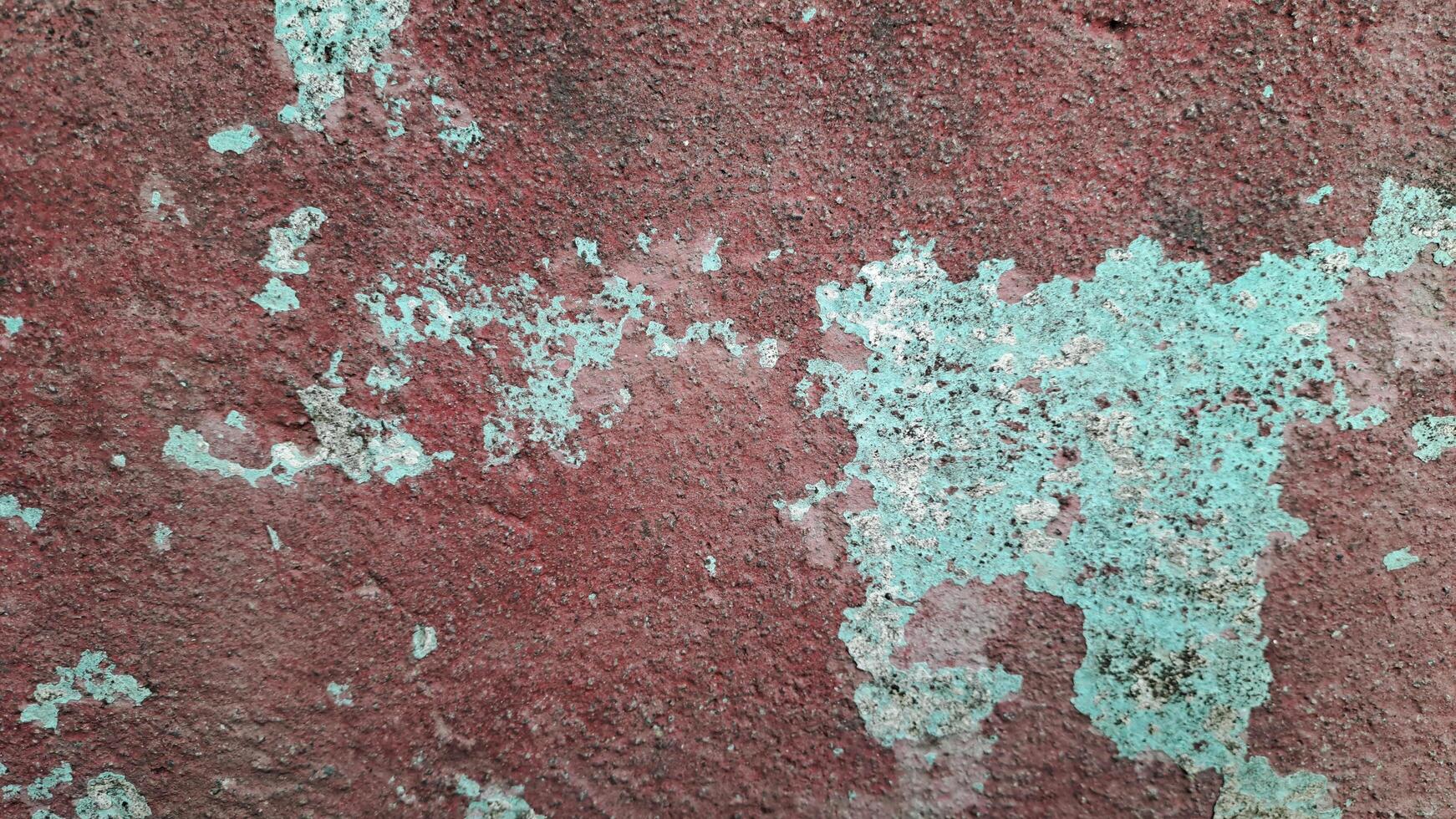 This weathered wall features peeling paint in shades of red and blue, creating a visually interesting and textured surface. photo