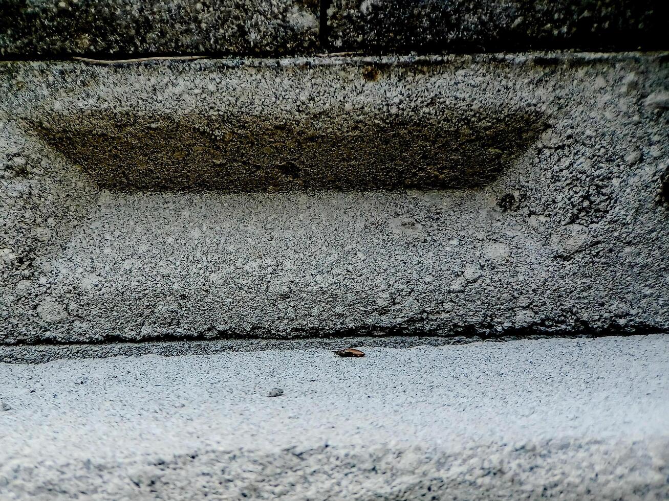 weathered concrete surface, showcasing the rough texture, cracks, and shadows created by its uneven surface. photo