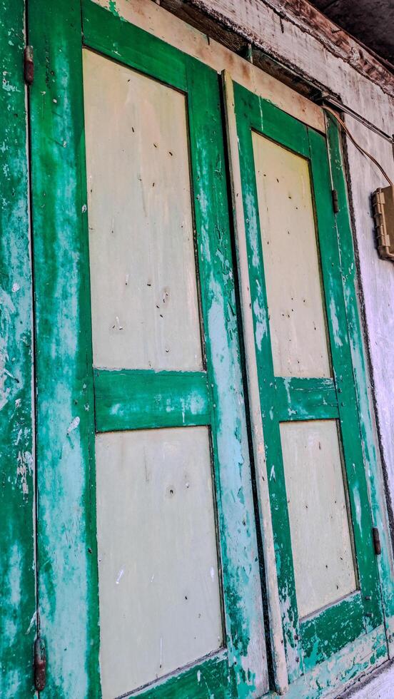features a pair of aged wooden window shutters painted in green and white. The shutters are weathered and distressed photo