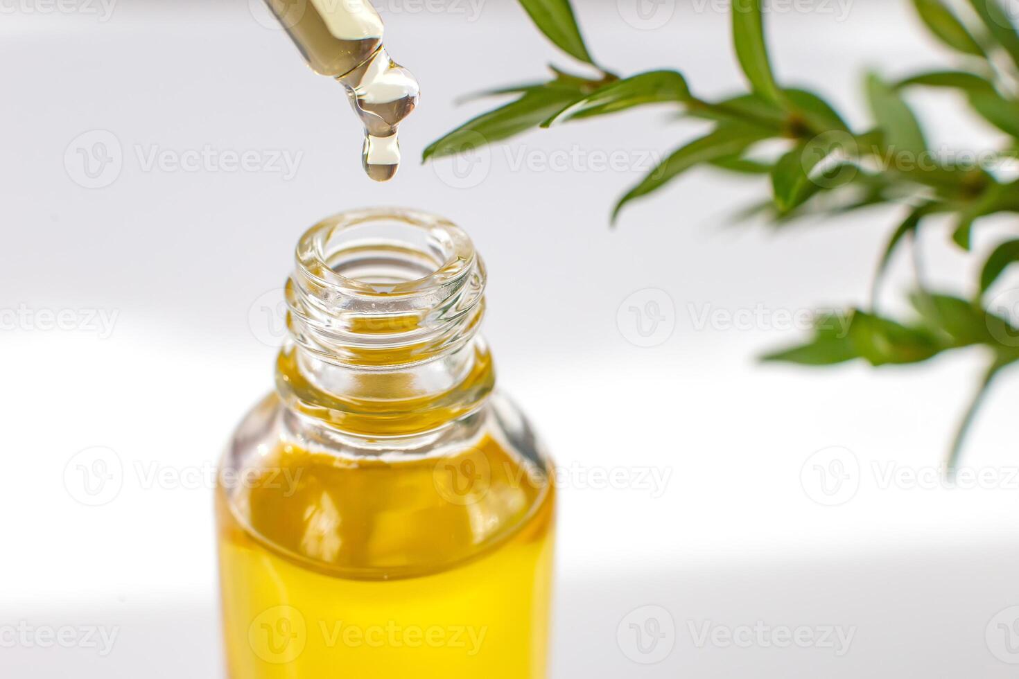 Close up yellow drop essential or organic oil in a glass pipette, over a bottle photo