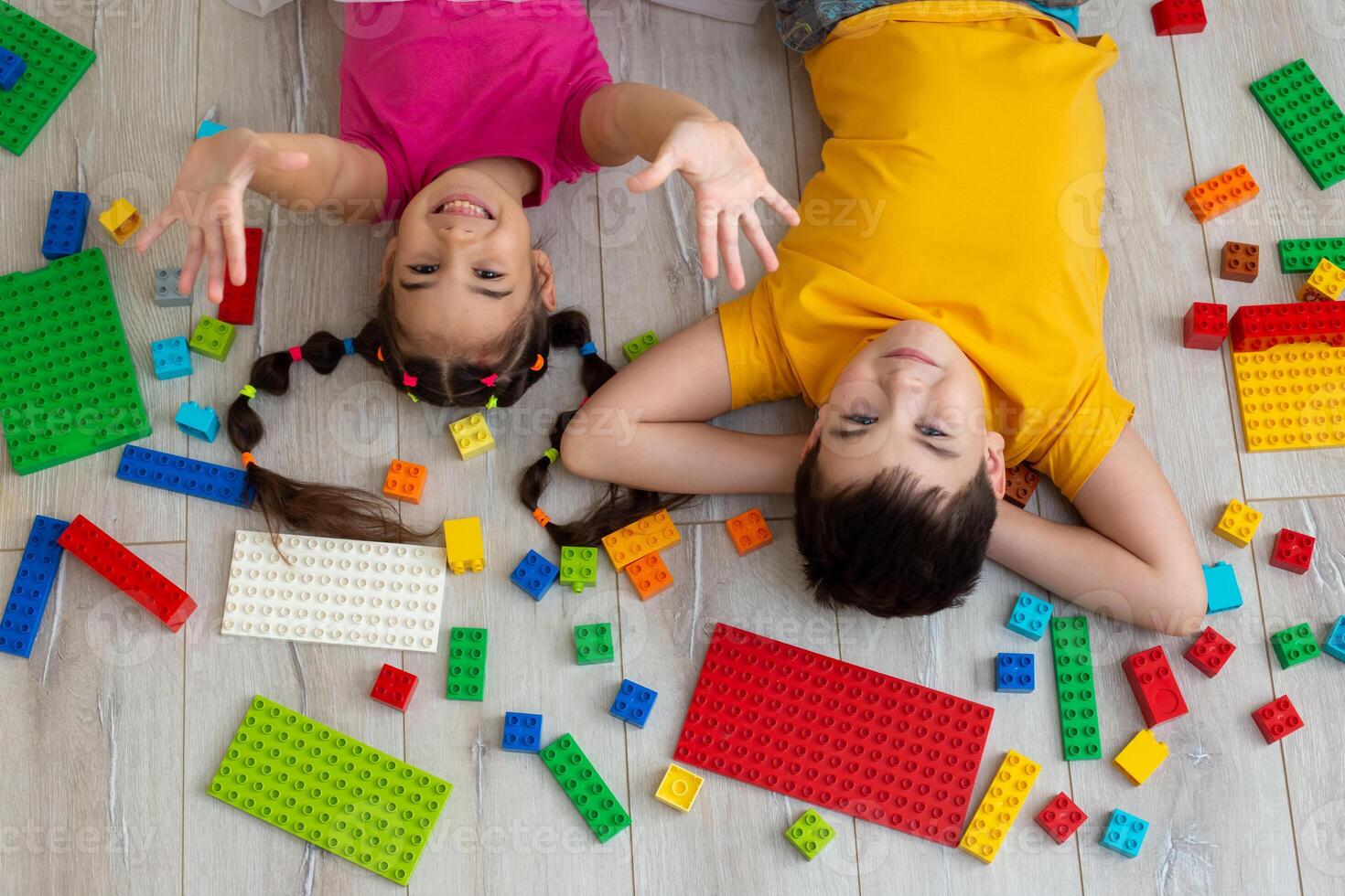 Portrait of happy boy and a little girl, lie on the floor with multicolor constructor photo
