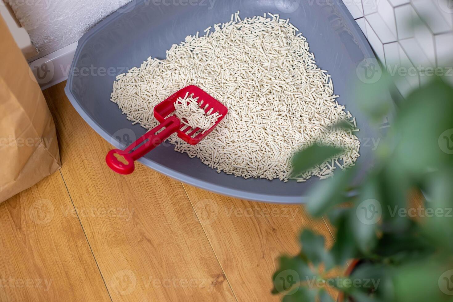 Grey plastic corner Tray for Cats with Granules of Natural Light Clumping filler and red scoop photo