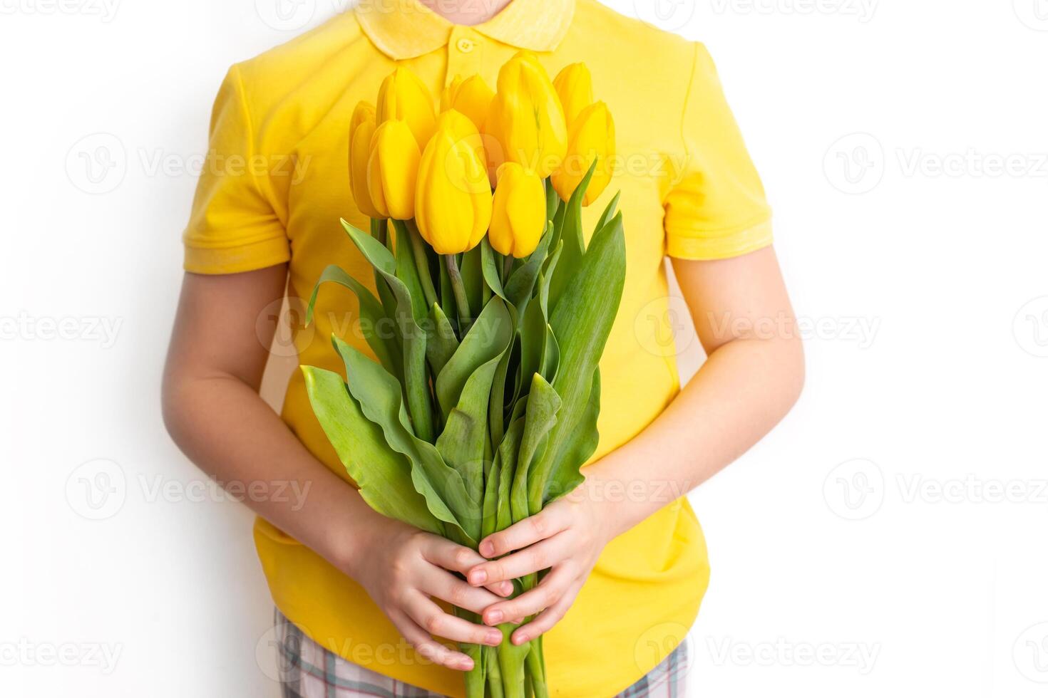 Boy in yellow t-shirt hold a bouquet of yellow tulips, stand on a white background, isolated photo