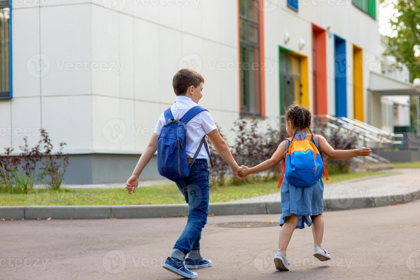 a little girl and a boy in a white shirt with backpacks run on the way to school. photo