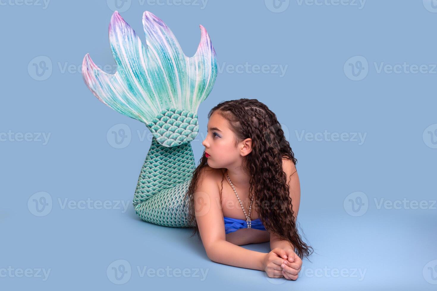 A pretty girl in a mermaid costume lie isolated on light-blue background photo