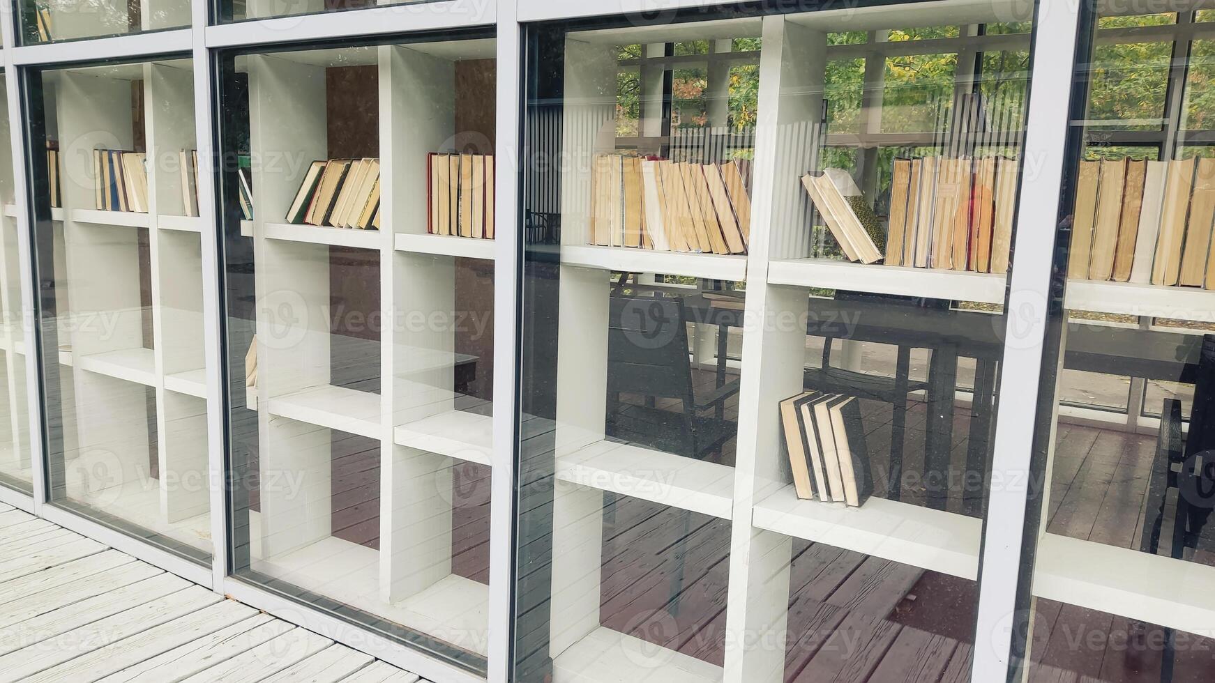 White shelving with books, behind glass, in summer photo