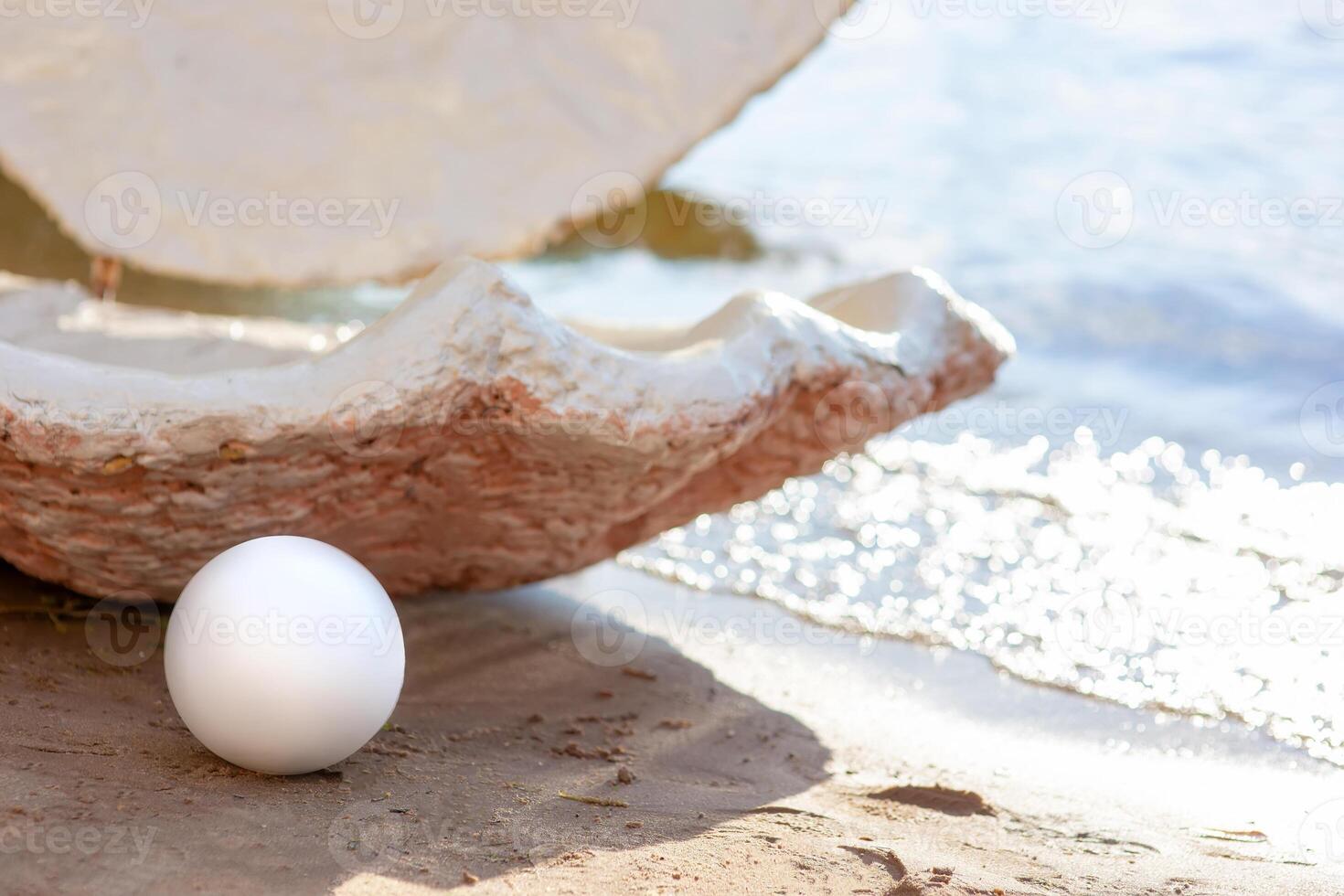 decorative open large seashell and a large white pearl, on the beach on a sunny day photo