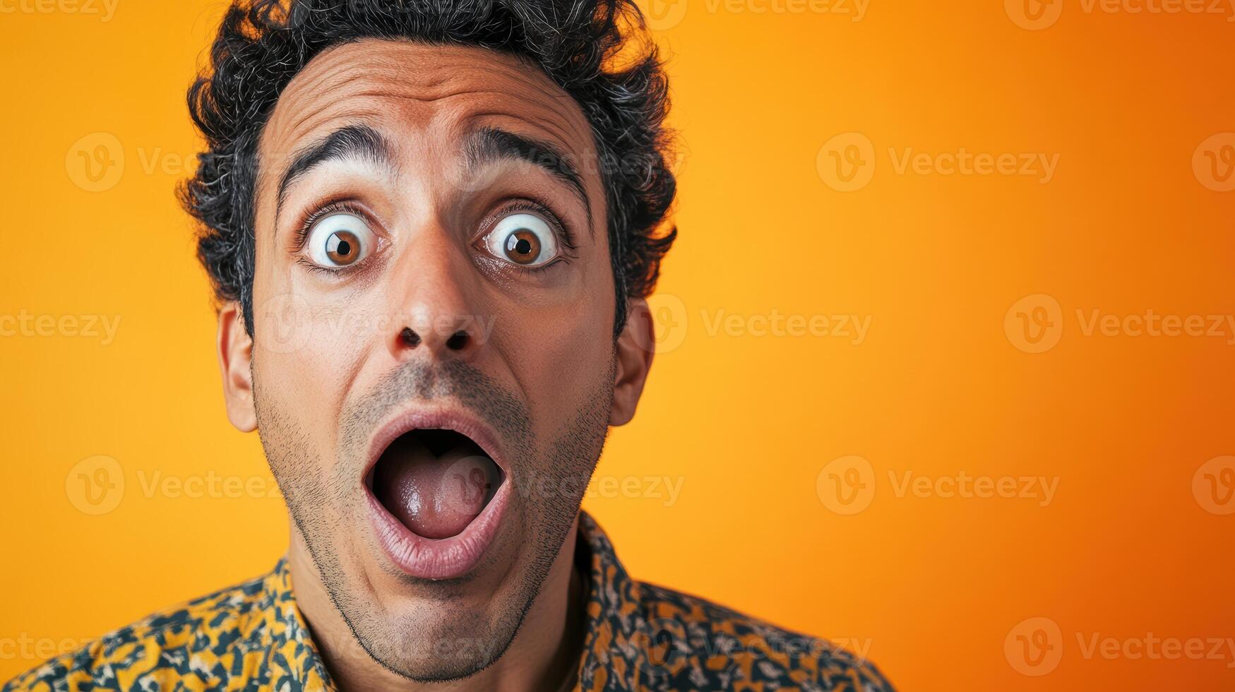 Close-up portrait of a surprised man with wide eyes and open mouth, expressing shock or amazement, set against a bright orange background. photo