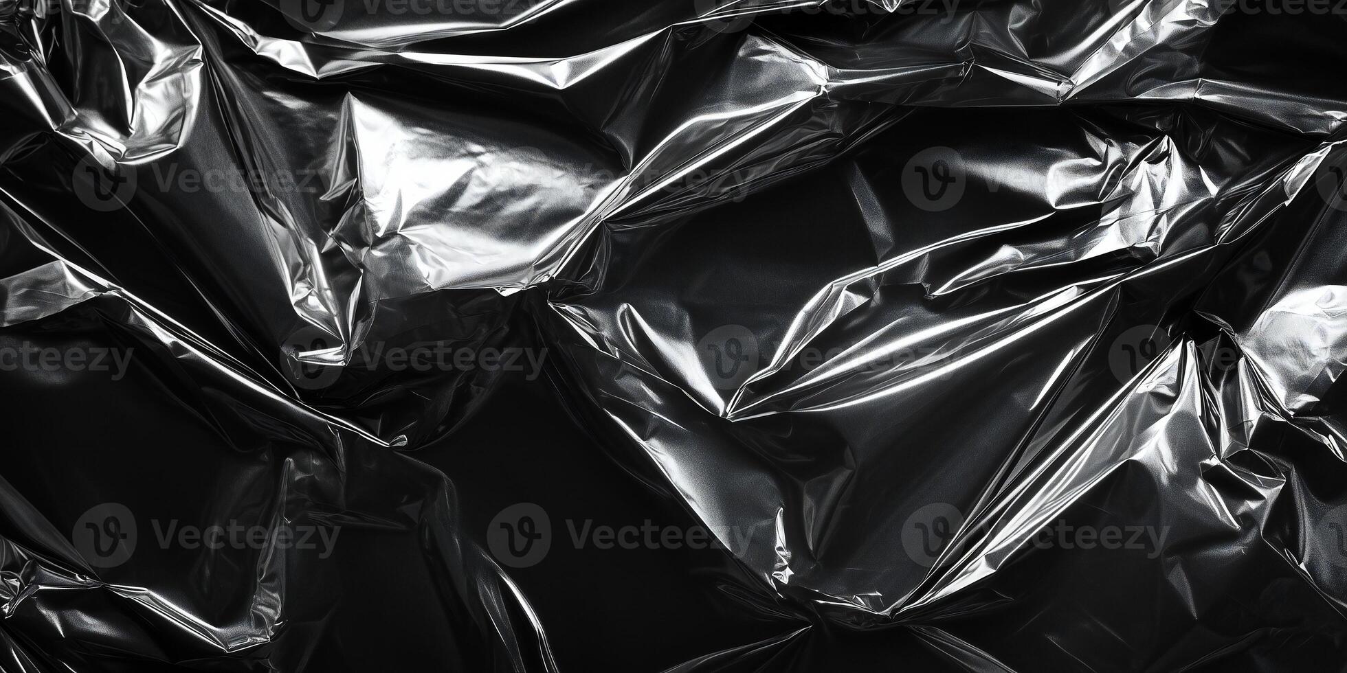 A close-up of crumpled metallic foil in a shiny silver color, creating a textured surface with reflective highlights and abstract folds. photo