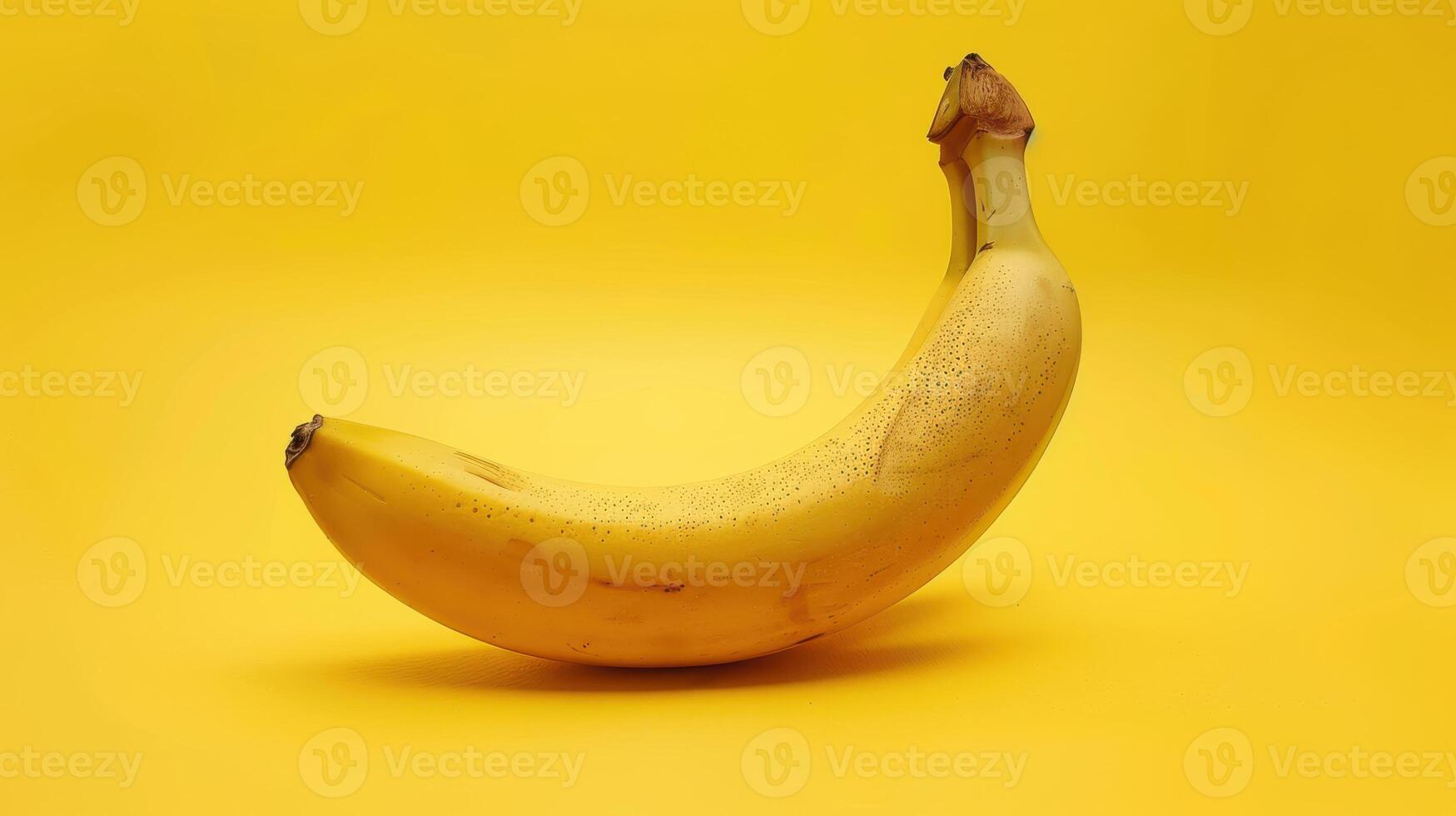 A Single Banana Curved on a Vibrant Yellow Background photo