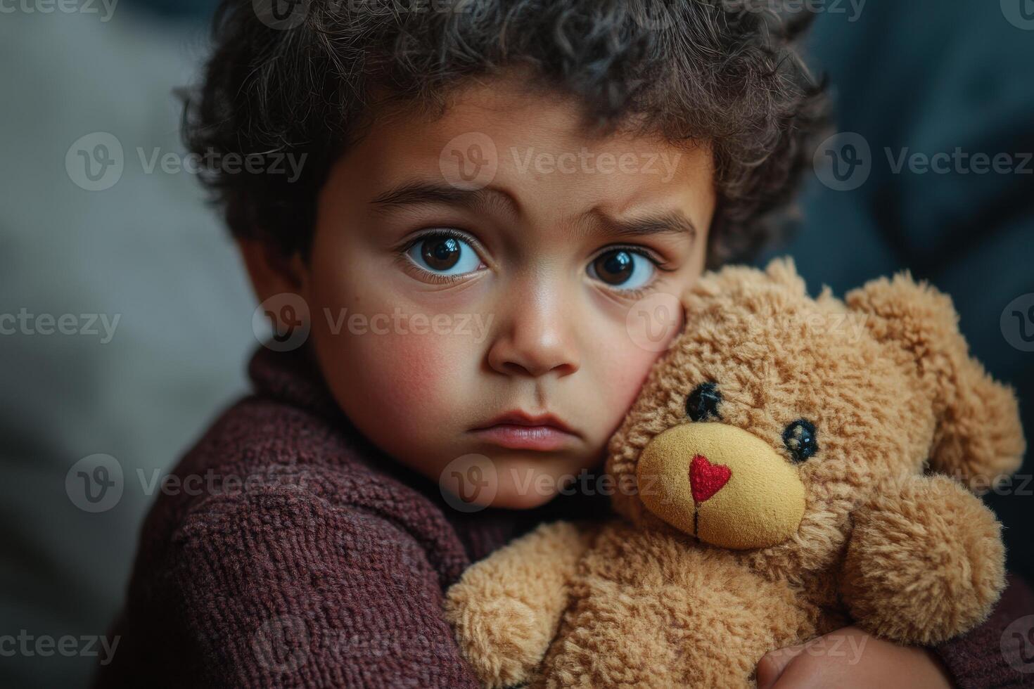 A child holding a bear gazes thoughtfully out of focus photo