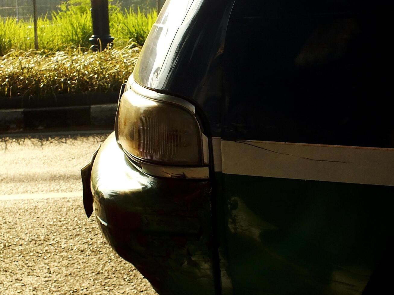 View from side of a car with a green stripe and white on the side. Close up selective focus head lamp photo