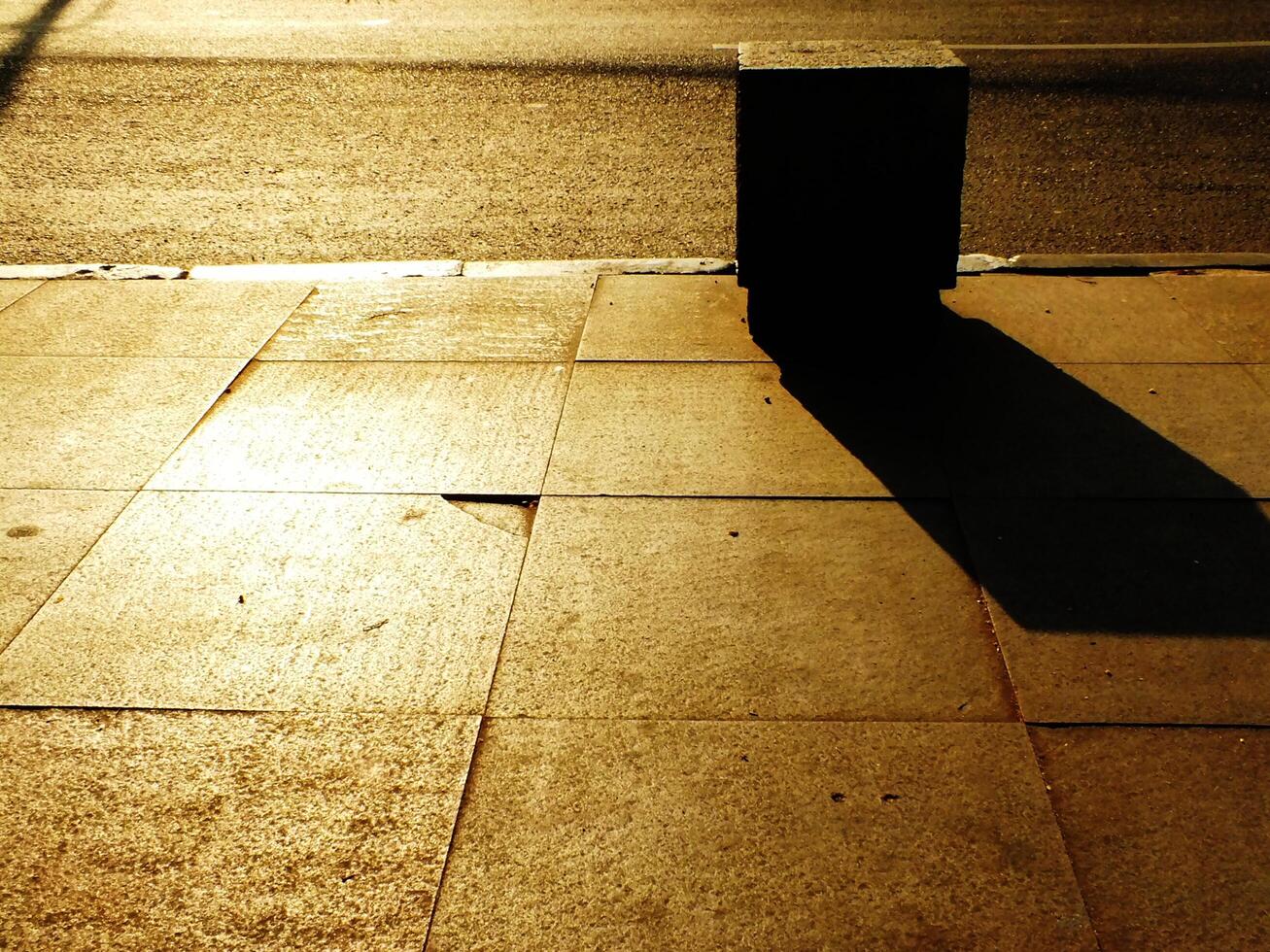 A sidewalk with a shadow of a stone box on it. Copy space for text photo