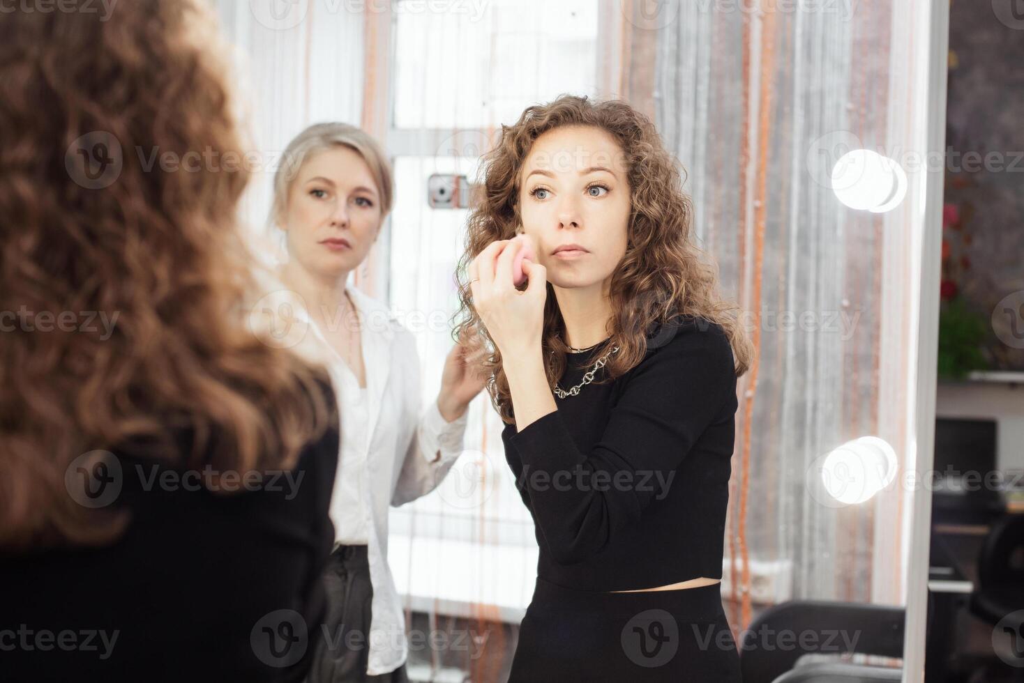A professional makeup artist conducts a master class on professional development, observing the student's work. photo