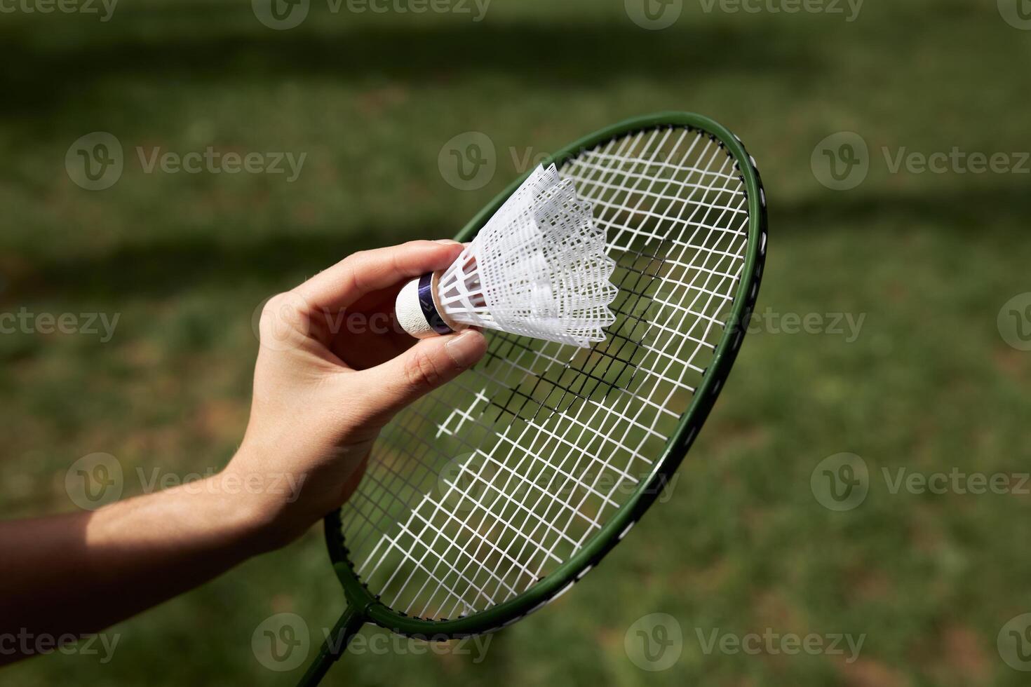 Close up view Badminton racket and shuttle outdoors isolated on green grass background. photo