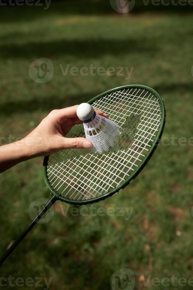 Close up view Badminton racket and shuttle outdoors isolated on green grass background. photo