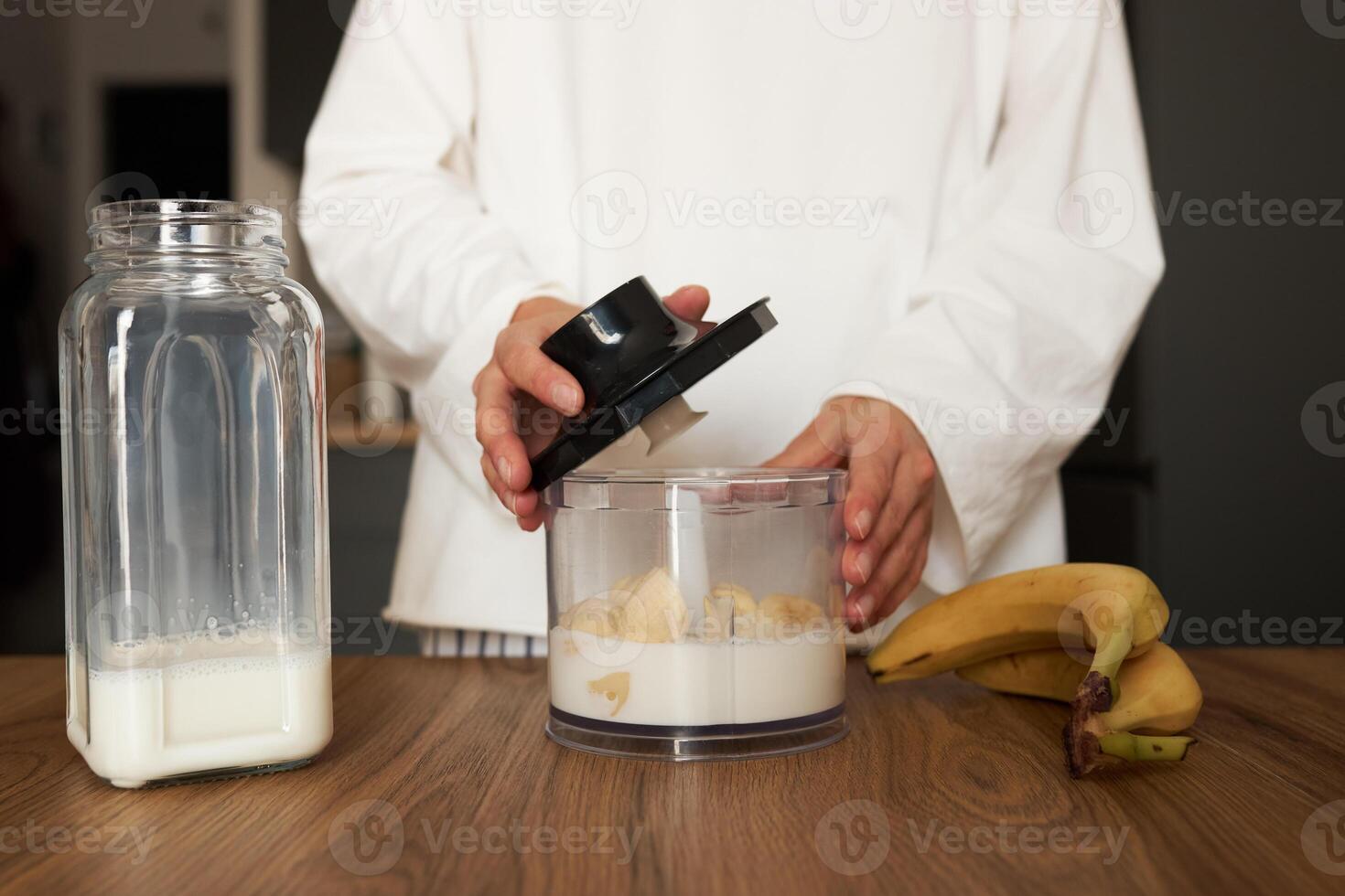 Woman preparing milkshake with blender at the kitchen photo