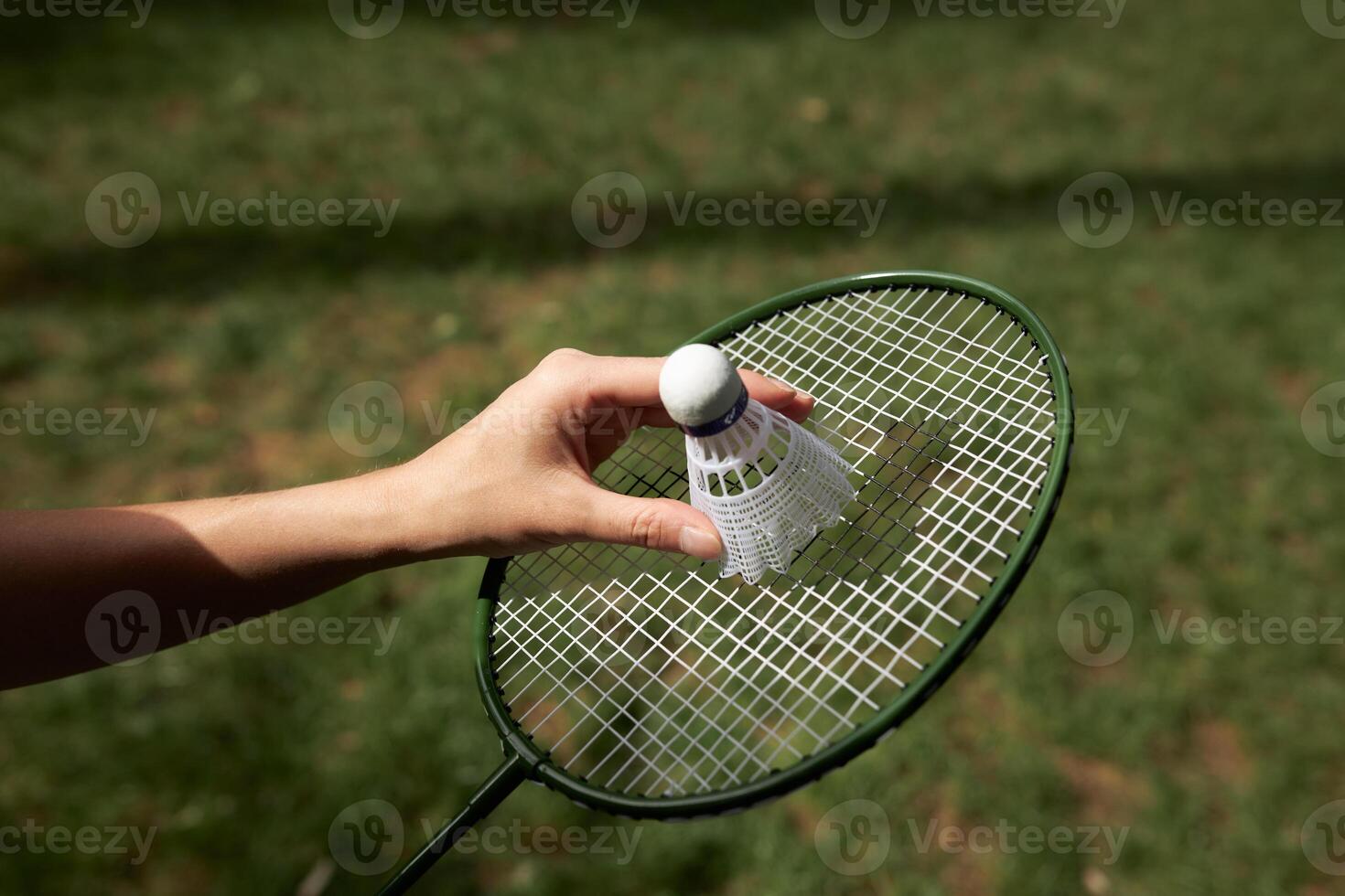 Close up view Badminton racket and shuttle outdoors isolated on green grass background. photo