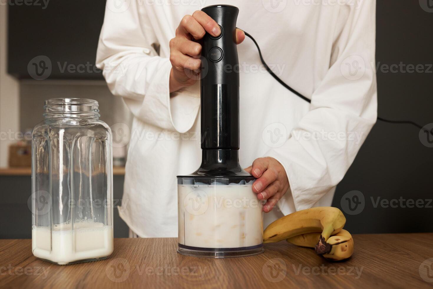 Woman preparing milkshake with blender at the kitchen photo