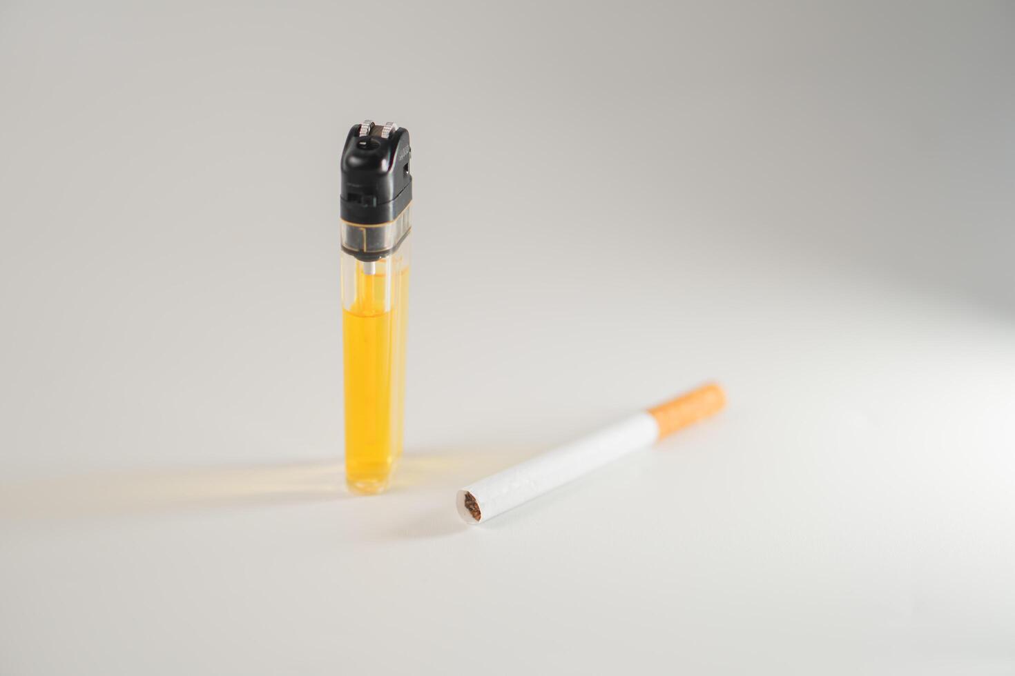 A cigarette and a lighter next to each other photo