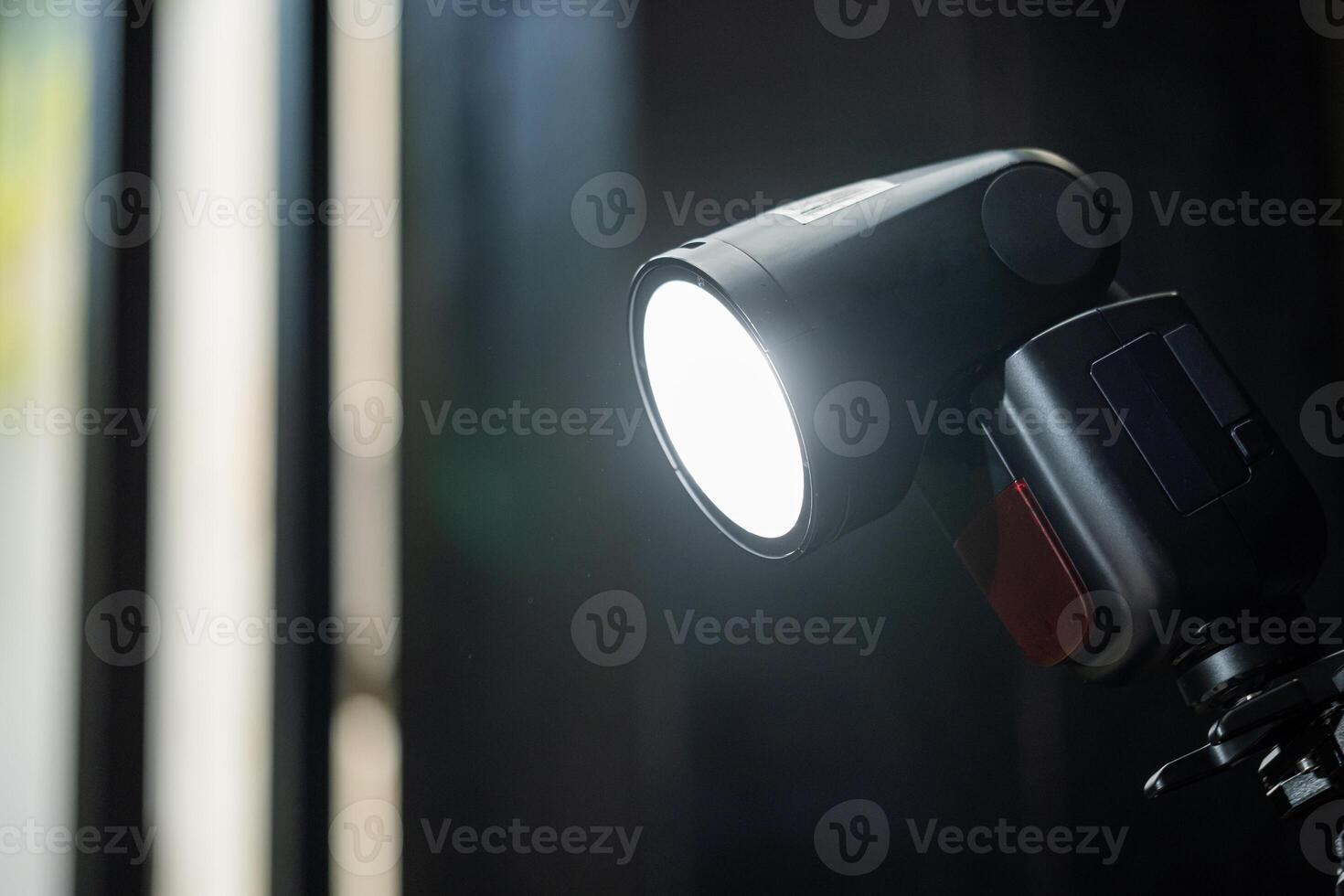 A flash light is on a tripod in front of a window photo