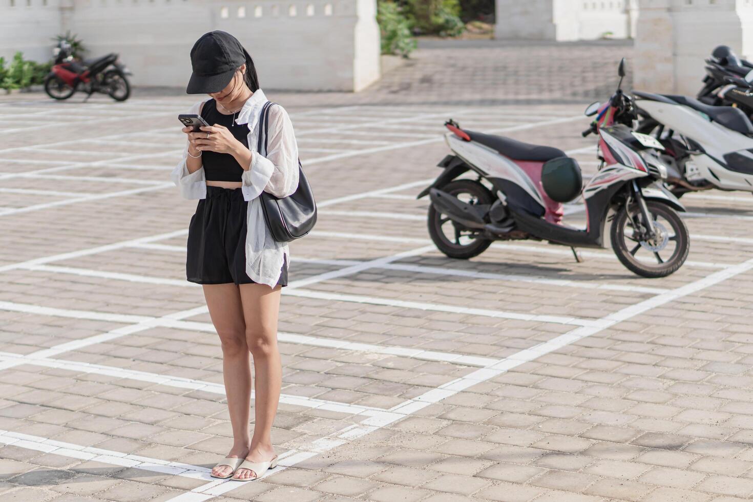 A woman standing in a parking lot with a cell phone photo