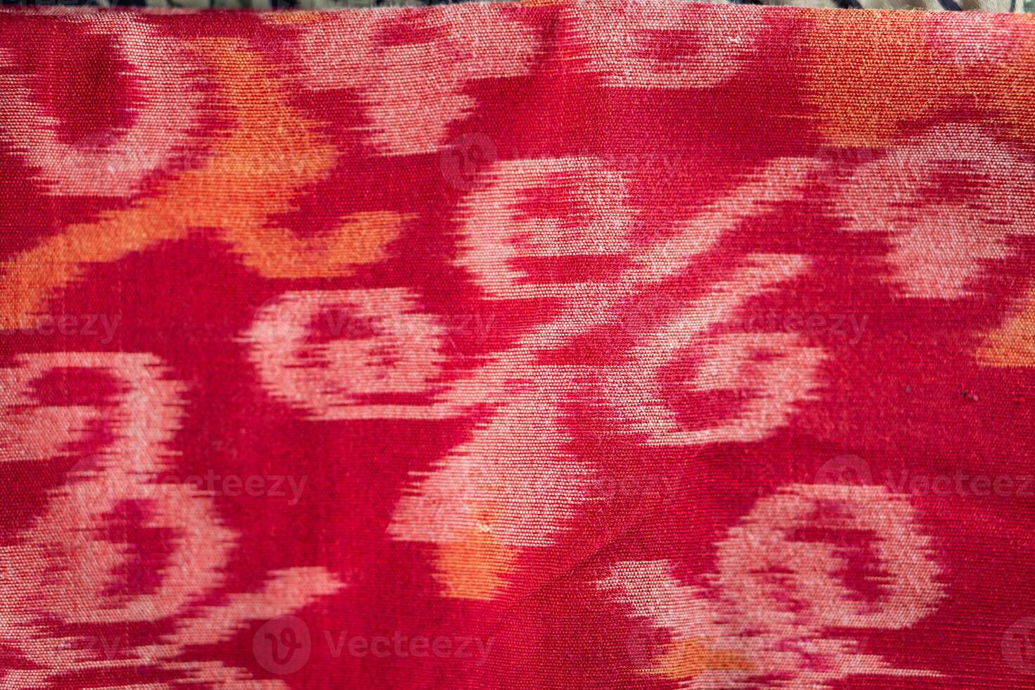 A red and orange ikat cloth with a pattern photo